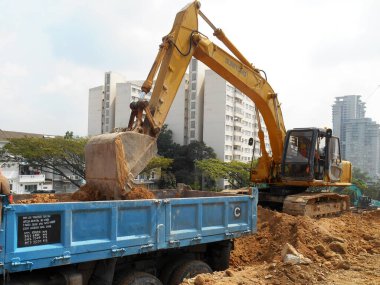 MELAKA, MALAYSIA - 6 Mart 2021: İnşaat alanında kazıcı makine. İnşaat alanında toprak ve diğer malzemelerin çıkarılması ve kaldırılması için kullanılır. Hidrolik bir kovayla güçlendirilmiş..  