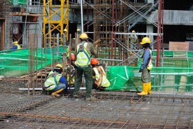 MALACCA, MALAYSIA - 30 Mart 2016: Malezya 'nın Malacca kentindeki inşaat alanında çelik takviye çubukları üreten inşaat işçileri. Destek çubuğu küçük bir kabloyla birbirine bağlanmış..  