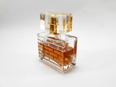 Beyaz arka planda turuncu parfüm sıvısı olan parfüm şişesi.