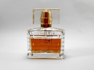 Beyaz arka planda turuncu parfüm sıvısı olan parfüm şişesi.