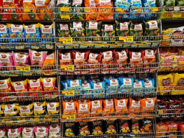 MELAKA, MALAYSIA -APRIL 19, 2022: Selective focused on packed miscellaneous brand junk foods and snacks on the rack and display for sale in the supermarket. Each has its own price tag. 