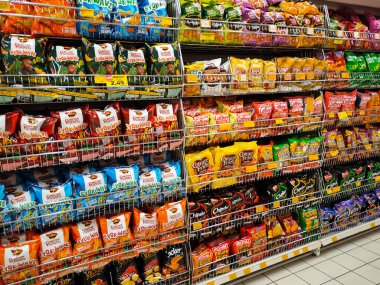 MELAKA, MALAYSIA -APRIL 19, 2022: Selective focused on packed miscellaneous brand junk foods and snacks on the rack and display for sale in the supermarket. Each has its own price tag. 