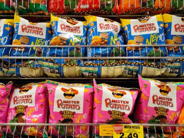 MELAKA, MALAYSIA -APRIL 19, 2022: Selective focused on packed miscellaneous brand junk foods and snacks on the rack and display for sale in the supermarket. Each has its own price tag. 