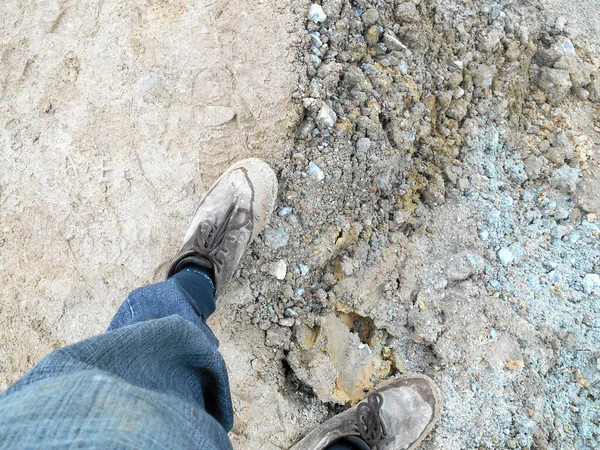 Top or side view of construction worker standing on construction site while wearing safety shoes. The shoes are dirty and dusty.