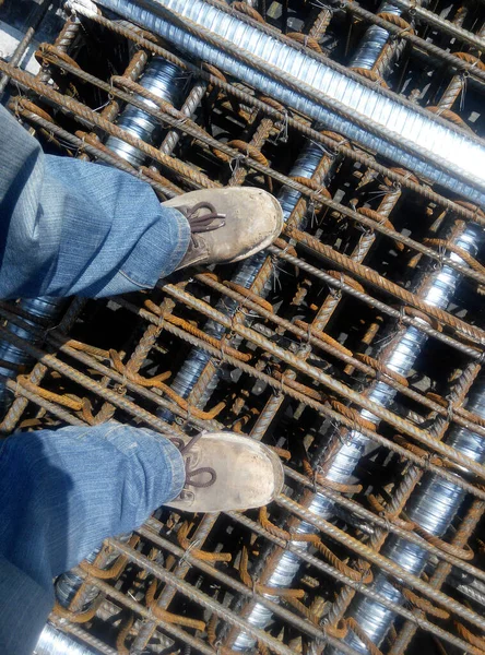 Top or side view of construction worker standing on construction site while wearing safety shoes. The shoes are dirty and dusty.