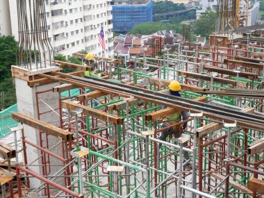 MELAKA, MALAYSIA -JULY 30, 2022: Construction workers are installing scaffolding at a construction site. They wear a safety harness as a safety measure to avoid accidents.