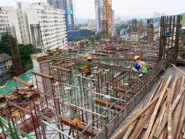 MELAKA, MALAYSIA -JULY 30, 2022: Construction workers are installing scaffolding at a construction site. They wear a safety harness as a safety measure to avoid accidents.
