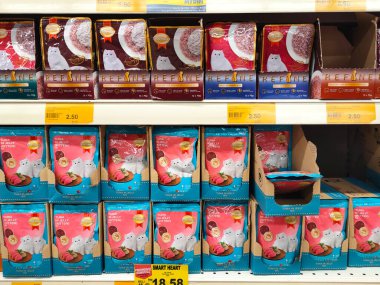 MELAKA, MALAYSIA -JANUARY 9, 2022: Cat food in commercial packs displayed for sale in a supermarket. Placed on the sales rack, and separated by brand and flavor. Has a price tag.