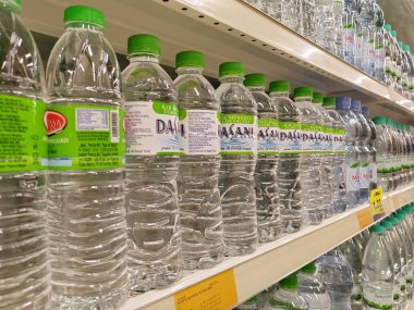KUALA LUMPUR, MALAYSIA -MAY 1, 2022: Mineral water is packaged in plastic bottles and labeled with various brands. Displayed on a shelf inside a supermarket. Placed with a price tag