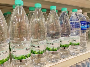 KUALA LUMPUR, MALAYSIA -MAY 1, 2022: Mineral water is packaged in plastic bottles and labeled with various brands. Displayed on a shelf inside a supermarket. Placed with a price tag