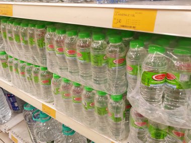 KUALA LUMPUR, MALAYSIA -MAY 1, 2022: Mineral water is packaged in plastic bottles and labeled with various brands. Displayed on a shelf inside a supermarket. Placed with a price tag