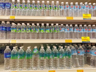 KUALA LUMPUR, MALAYSIA -MAY 1, 2022: Mineral water is packaged in plastic bottles and labeled with various brands. Displayed on a shelf inside a supermarket. Placed with a price tag