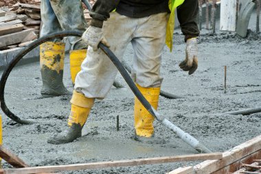 SELANGOR, MALAYSIA -AUGUST 26, 2015: Construction workers using a concrete vibrator at the construction site to compact concrete slurry that pour in the form work. 
