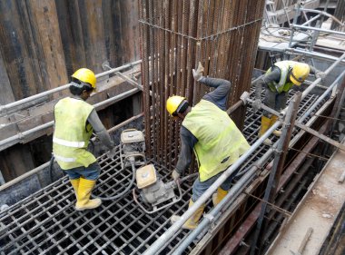 SELANGOR, MALAYSIA -AUGUST 26, 2015: Construction workers using a concrete vibrator at the construction site to compact concrete slurry that pour in the form work. 