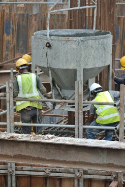 SELANGOR, MALAYSIA -DECEMBER 12, 2015: A group of construction workers pouring concrete using concrete bucket into the pile cap form work at the construction site.  