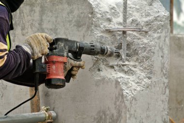 JOHOR, MALAYSIA -OCTOBER 20, 2015: A construction workers hacking concrete column using small heavy duty mobile hacker machine at the construction site.   