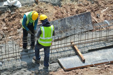 MALACCA, MALAYSIA -MARCH 29, 2016: Construction workers fabricating steel reinforcement bar at the construction site in Malacca, Malaysia. The reinforcement bar was ties together using tiny wire.  