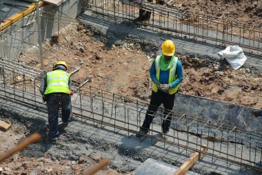 MALACCA, MALAYSIA -MARCH 29, 2016: Construction workers fabricating steel reinforcement bar at the construction site in Malacca, Malaysia. The reinforcement bar was ties together using tiny wire.  