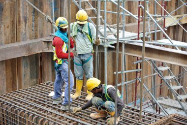 JOHOR, MALAYSIA - MARCH 03, 2015: Construction workers fabricating pile cap steel reinforcement bar at the construction site.  