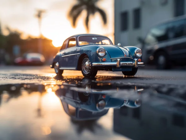 Miniature classic car model with a backdrop of evening sun bokeh. The car model\'s image can be reflected in the puddle in front of it.
