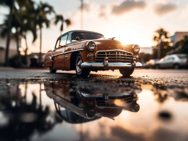 Miniature classic car model with a backdrop of evening sun bokeh. The car model\'s image can be reflected in the puddle in front of it.