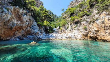 Yunanistan 'ın Amarandos adası yakınlarında el değmemiş turkuaz suyu ve gizli çakıl taşı plajı olan tenha bir koy.