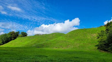 Eski Aizkraukle Hillfort 'un cennet gibi yeşil tepeleri Letonya' da beyaz bulutlarla dolu güzel mavi bir gökyüzünün altında..