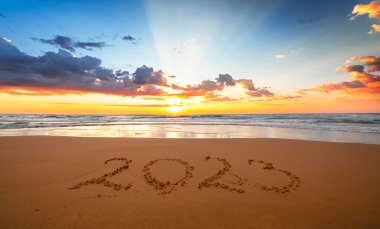 2023 ile güzel bir gün batımı! Mutlu yıllar 2023 konsepti! Yıl 2023 Sahilde kumsalda, arkada deniz yazılıydı.