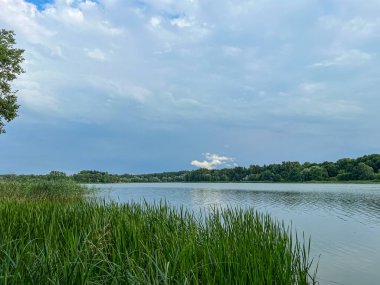 Sakin sular, doğanın güzelliğinin ahenkli bir karışımını yaratan canlı gökyüzünü yansıtır. Huzurlu sahne bir sükunet ve sükunet hissi yayar.