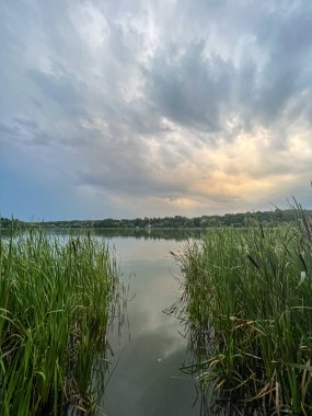 Sakin sular, doğanın güzelliğinin ahenkli bir karışımını yaratan canlı gökyüzünü yansıtır. Huzurlu sahne bir sükunet ve sükunet hissi yayar.