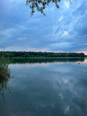 Sakin sular, doğanın güzelliğinin ahenkli bir karışımını yaratan canlı gökyüzünü yansıtır. Huzurlu sahne bir sükunet ve sükunet hissi yayar.