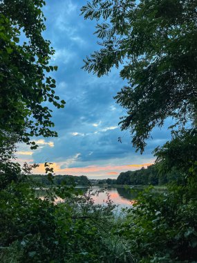 Sakin sular, doğanın güzelliğinin ahenkli bir karışımını yaratan canlı gökyüzünü yansıtır. Huzurlu sahne bir sükunet ve sükunet hissi yayar.