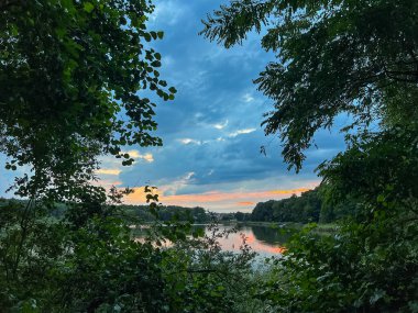 Sakin sular, doğanın güzelliğinin ahenkli bir karışımını yaratan canlı gökyüzünü yansıtır. Huzurlu sahne bir sükunet ve sükunet hissi yayar.