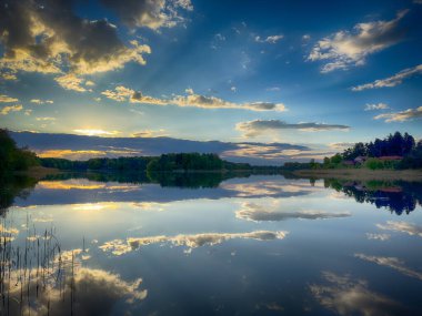 Huzurlu Balık Gölü: tenha bir balıkçı gölünün sakin sularında huzurlu bir manzara. Bereketli yeşilliklerle çevrili ve berrak mavi gökyüzü ile çerçevelenmiş bu resim mükemmel bir günün özünü yakalıyor. 