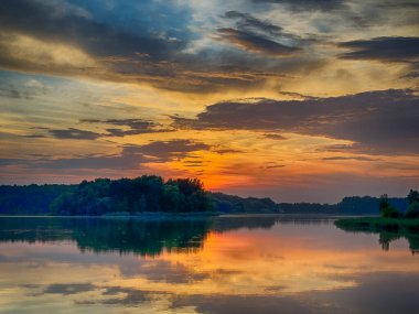 Huzurlu Balık Gölü: tenha bir balıkçı gölünün sakin sularında huzurlu bir manzara. Bereketli yeşilliklerle çevrili ve berrak mavi gökyüzü ile çerçevelenmiş bu resim mükemmel bir günün özünü yakalıyor. 