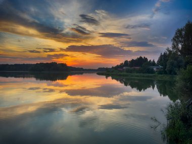 Huzurlu Balık Gölü: tenha bir balıkçı gölünün sakin sularında huzurlu bir manzara. Bereketli yeşilliklerle çevrili ve berrak mavi gökyüzü ile çerçevelenmiş bu resim mükemmel bir günün özünü yakalıyor. 