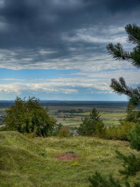 Dramatik bulutlu gökyüzünün altındaki köyün tepe manzarası. Yağmurdan önce kırsal köy manzarası