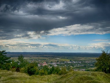Dramatik bulutlu gökyüzünün altındaki köyün tepe manzarası. Yağmurdan önce kırsal köy manzarası