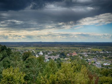 Dramatik bulutlu gökyüzünün altındaki köyün tepe manzarası. Yağmurdan önce kırsal köy manzarası