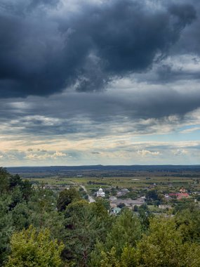 Dramatik bulutlu gökyüzünün altındaki köyün tepe manzarası. Yağmurdan önce kırsal köy manzarası