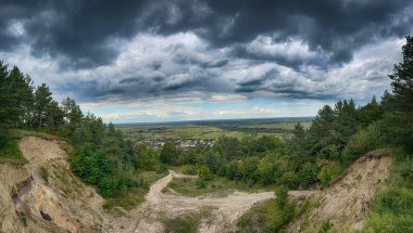 Dramatik bulutlu gökyüzünün altındaki köyün tepe manzarası. Yağmurdan önce kırsal köy manzarası