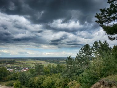 Dramatik bulutlu gökyüzünün altındaki köyün tepe manzarası. Yağmurdan önce kırsal köy manzarası