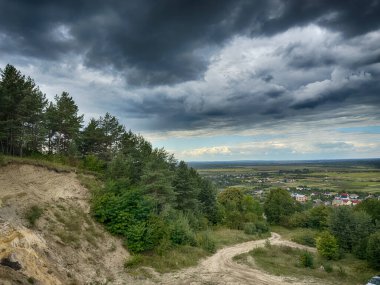Dramatik bulutlu gökyüzünün altındaki köyün tepe manzarası. Yağmurdan önce kırsal köy manzarası