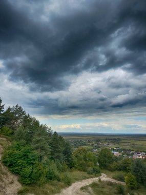Dramatik bulutlu gökyüzünün altındaki köyün tepe manzarası. Yağmurdan önce kırsal köy manzarası