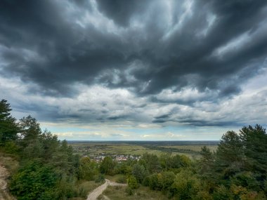 Dramatik bulutlu gökyüzünün altındaki köyün tepe manzarası. Yağmurdan önce kırsal köy manzarası