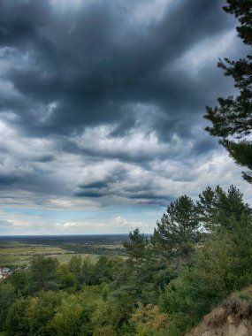 Dramatik bulutlu gökyüzünün altındaki köyün tepe manzarası. Yağmurdan önce kırsal köy manzarası