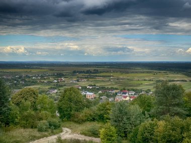 Dramatik bulutlu gökyüzünün altındaki köyün tepe manzarası. Yağmurdan önce kırsal köy manzarası