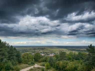 Dramatik bulutlu gökyüzünün altındaki köyün tepe manzarası. Yağmurdan önce kırsal köy manzarası