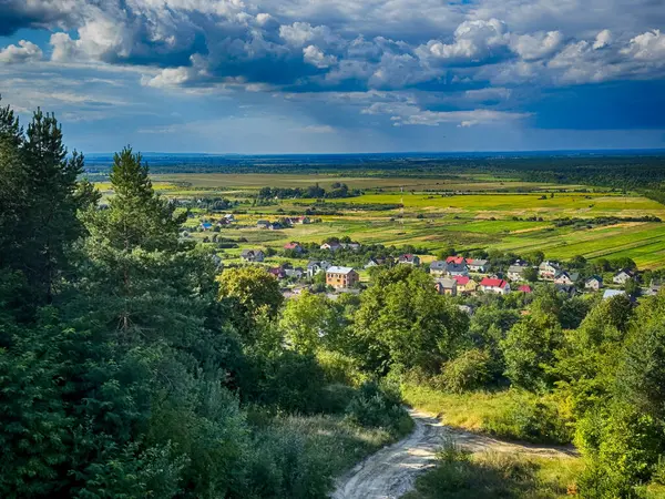Dramatik bulutlu gökyüzünün altındaki köyün tepe manzarası. Yağmurdan önce kırsal köy manzarası
