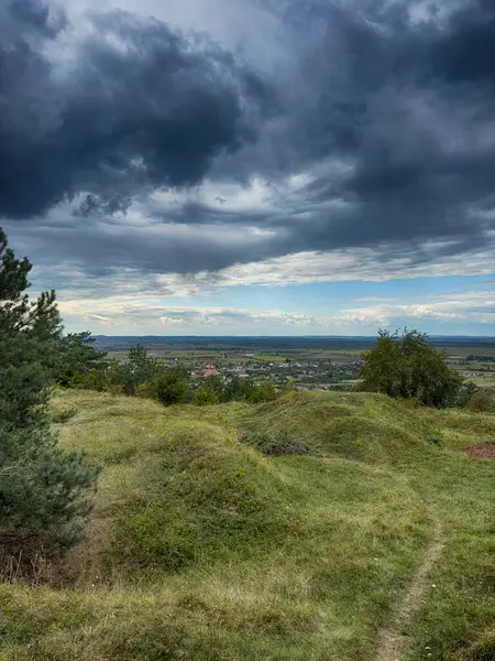 Dramatik bulutlu gökyüzünün altındaki köyün tepe manzarası. Yağmurdan önce kırsal köy manzarası